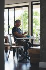 Homme d'affaires utilisant un téléphone portable tout en prenant le petit déjeuner au bureau — Photo de stock
