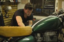 Mecânico usando laptop durante a reparação de moto na garagem — Fotografia de Stock