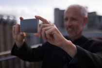 Empresário tirando fotos no celular na varanda do hotel — Fotografia de Stock