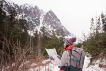 Belle femme regardant la carte pendant la randonnée en hiver — Photo de stock