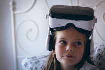 Дівчина з гарнітурою віртуальної реальності сидить на ліжку вдома — стокове фото