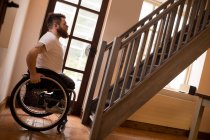 Vista lateral del hombre discapacitado en silla de ruedas mirando escaleras - foto de stock