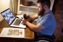Uomo disabile guardando le foto in macchina fotografica a casa — Foto stock