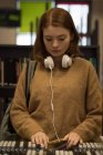 Jeune femme ramassant cassette à la bibliothèque — Photo de stock