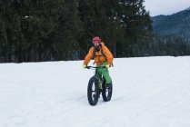 Homem andando de bicicleta em uma paisagem nevada durante o inverno — Fotografia de Stock