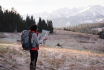 Frau schaut im Winter beim Wandern auf Landkarte — Stockfoto