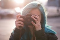 Стильная женщина фотографируется с камерой на городской улице — стоковое фото