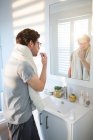 Homme brossant ses dents dans la salle de bain à la maison — Photo de stock