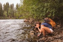 Seitenansicht einer Frau, die Wasser aus dem Fluss trinkt — Stockfoto