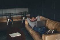Бізнесмен використовує ноутбук на дивані в офісі — стокове фото