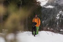 Человек гуляет со своей собакой по снежному пейзажу зимой — стоковое фото