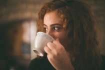 Mulher atenciosa tomando xícara de café em casa — Fotografia de Stock