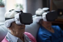 Amici anziani che utilizzano cuffie realtà virtuale a casa — Foto stock