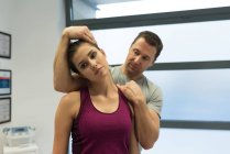 Физиотерапевт делает массаж шеи женщине в клинике — стоковое фото