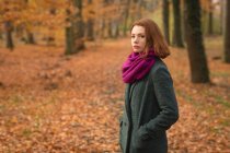 Жінка стоїть з рукою в кишені в парку восени — стокове фото