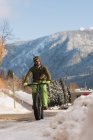 Человек ездит на велосипеде по тротуару зимой — стоковое фото