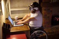 Людина з обмеженими можливостями у гарнітурі віртуальної реальності, використовуючи ноутбук вдома — стокове фото