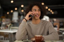 Young man talking on mobile phone in restaurant — Stock Photo