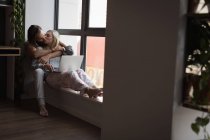 Coppia baciarsi mentre si utilizza il computer portatile a casa — Foto stock