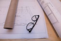 Blueprint and spectacle on table in office — Stock Photo