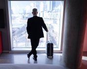 Empresário olhando para fora da janela no quarto de hotel — Fotografia de Stock