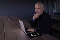 Geschäftsmann denkt tief nach, während er Laptop im Hotel benutzt — Stockfoto