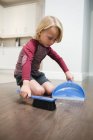Ragazzo spazzare polvere con spazzola e padella a casa — Foto stock
