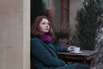 Удумлива жінка має чашку кави у відкритому кафе — стокове фото