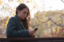 Молода жінка використовує мобільний телефон у парку — стокове фото
