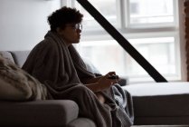 Schöne Frau spielt Videospiel, während sie es sich auf dem Sofa im Wohnzimmer gemütlich macht — Stockfoto