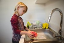 Menino lavando um pano de pano na cozinha em casa — Fotografia de Stock