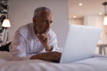 Geschäftsmann mit Laptop auf Bett im Hotelzimmer — Stockfoto