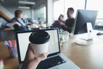 Бизнесмен пьет кофе, пока коллеги обсуждают в офисе — стоковое фото