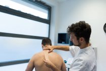 Physiotherapist applying bandage on patients back in clinic — Stock Photo