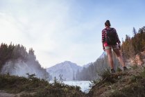 Rückansicht einer Frau mit Rucksack beim Anblick eines Wasserfalls — Stockfoto