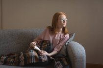 Продумана дівчина читає книгу у вітальні вдома — стокове фото