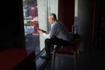 Nachdenklicher Geschäftsmann benutzt Handy im Hotelzimmer — Stockfoto