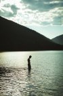Silhouette dell'uomo in piedi in un lago — Foto stock