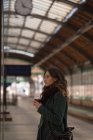Thoughtful woman having coffee at railway station — Stock Photo