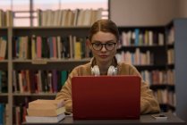 Jovem mulher usando um laptop na biblioteca — Fotografia de Stock