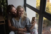 Casal tirando selfie com celular em casa — Fotografia de Stock