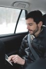 Giovane uomo che utilizza tablet digitale in un'auto — Foto stock