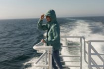 Mulher de capuz de pé no navio de cruzeiro em um dia ensolarado — Fotografia de Stock