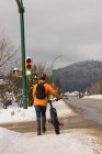 Vista trasera del hombre caminando con su bicicleta en la acera durante el invierno - foto de stock