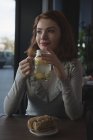Mujer sonriente tomando té de limón en la cafetería - foto de stock