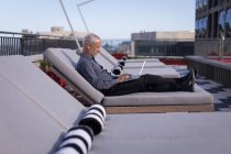 Uomo d'affari che utilizza un computer portatile mentre riposa su un lettino in hotel — Foto stock