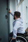 Людина з обмеженими можливостями дзвонить до дверей свого будинку — стокове фото