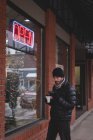 Молодий чоловік використовує мобільний телефон за межами магазину — стокове фото