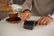 Homem fazendo pagamento através de cartão de débito na cafetaria — Fotografia de Stock