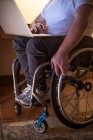 Sección baja del hombre discapacitado usando el ordenador portátil en casa - foto de stock